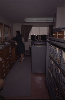 Color view of two women working in a filing area helping patrons.