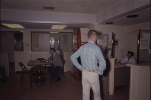 Color view of three people in a shared office and break room area.