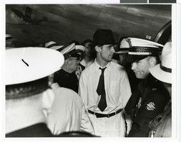 Photograph of Howard Hughes next to an airplane and surrounded by crowds at Houston Airport, Texas, July, 30, 1938