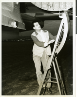 Photograph of Howard Hughes on ladder under the XF-11, April 3, 1947