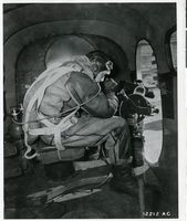 Photograph of photographer/cameraman filiming on an airplane, circa 1940s-1950s