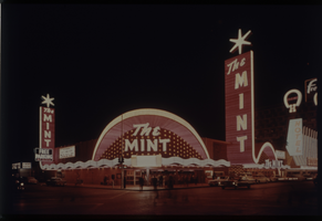 Color view of The Mint at night. Neon signs for Binion's Horseho and the Fremont Hotel are visible in the background.