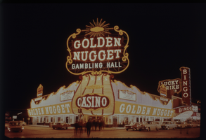 Color view of the Golden Nugget Gambling Hall at night. A neon sign for the Lucky Strike Club is visible in the background.