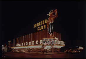 Color view of the New Pioneer Club at night, featuring a neon sculpture of "Vegas Vic."