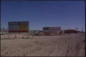 Color view of Sunrise Center and Montgomery Wards department store construction site signs located at Charleston and Fremont Street. The building was converted to a Lowe's after Wards closed in. Frenchman mountain (aka Sunrise Mountain) is visible in the background.
