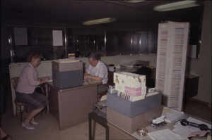 Color view of two people in a shared office area.