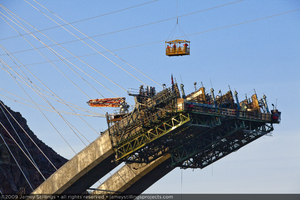Photograph of ironworkers being transported in manbaskets during Mike O'Callaghan-Pat Tillman Memorial Bridge construction, Nevada-Arizona border, April 30, 2009