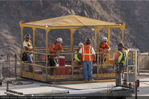 Photograph of ironworkers and a manbasket during construction of the Mike O'Callaghan-Pat Tillman Memorial Bridge, Nevada-Arizona border, July 1, 2009