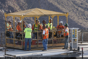 Photograph of ironworkers in a manbasket during construction of Mike O'Callaghan-Pat Tillman Memorial Bridge, Nevada-Arizona border, July 1, 2009