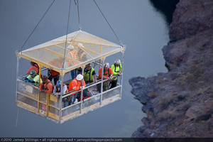 Photograph of ironworkers being transported in a manbasket over the Mike O'Callaghan-Pat Tillman Memorial Bridge during construction, Nevada border, February 2, 2010