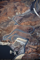 Photograph showing an aerial view of the original winding road descending to Hoover Dam with the new bypass road under construction in the upper right, Arizona border, February 3, 2010