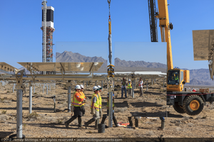 Photograph of workers walking by installed heliostat, June 4, 2012