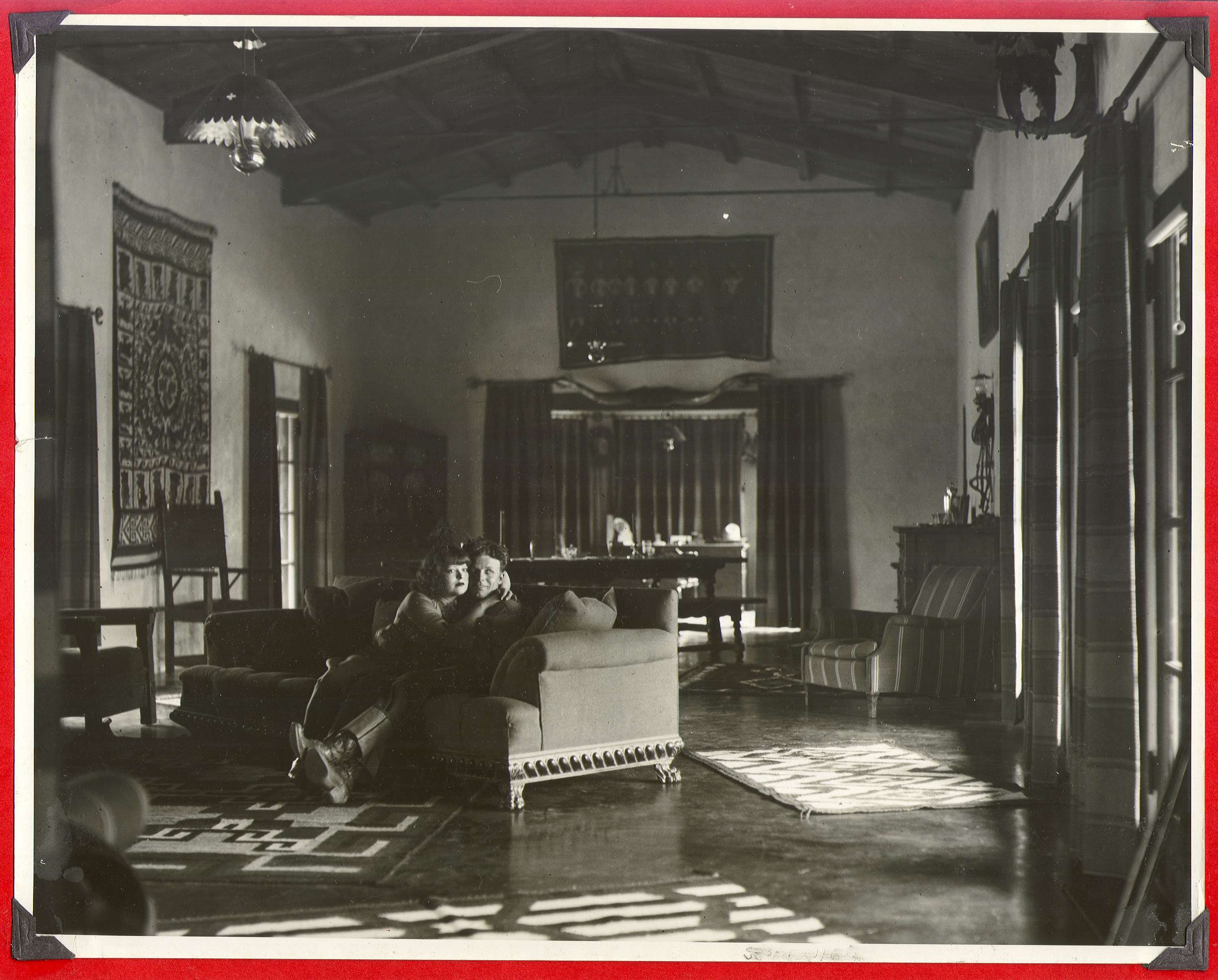 Clara Bow and Rex Bell sitting on a couch in the living room of the ranch: photographic print