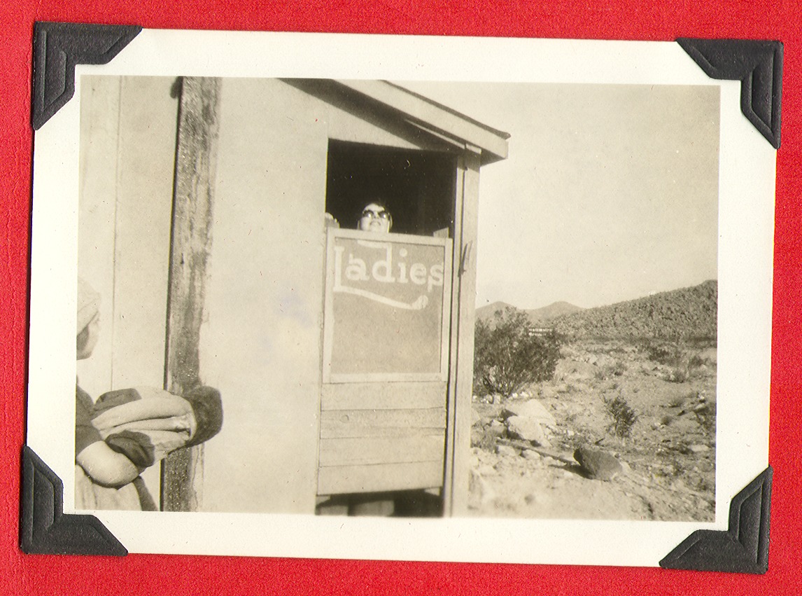 Someone peeking over the "Ladies" sign at an outhouse: photographic print
