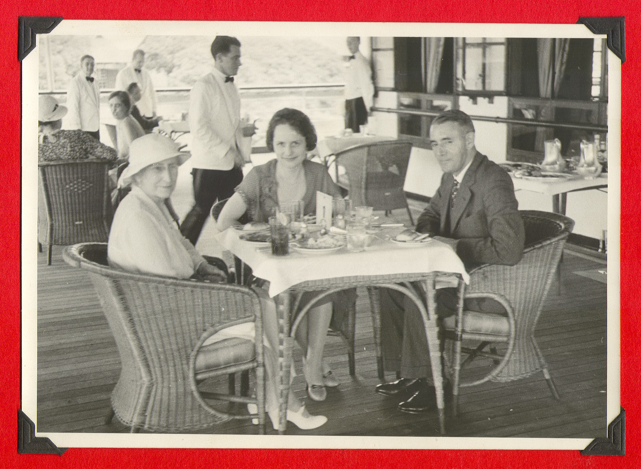 Two women and a man seated at a table in a restaurant (unidentified): photographic print