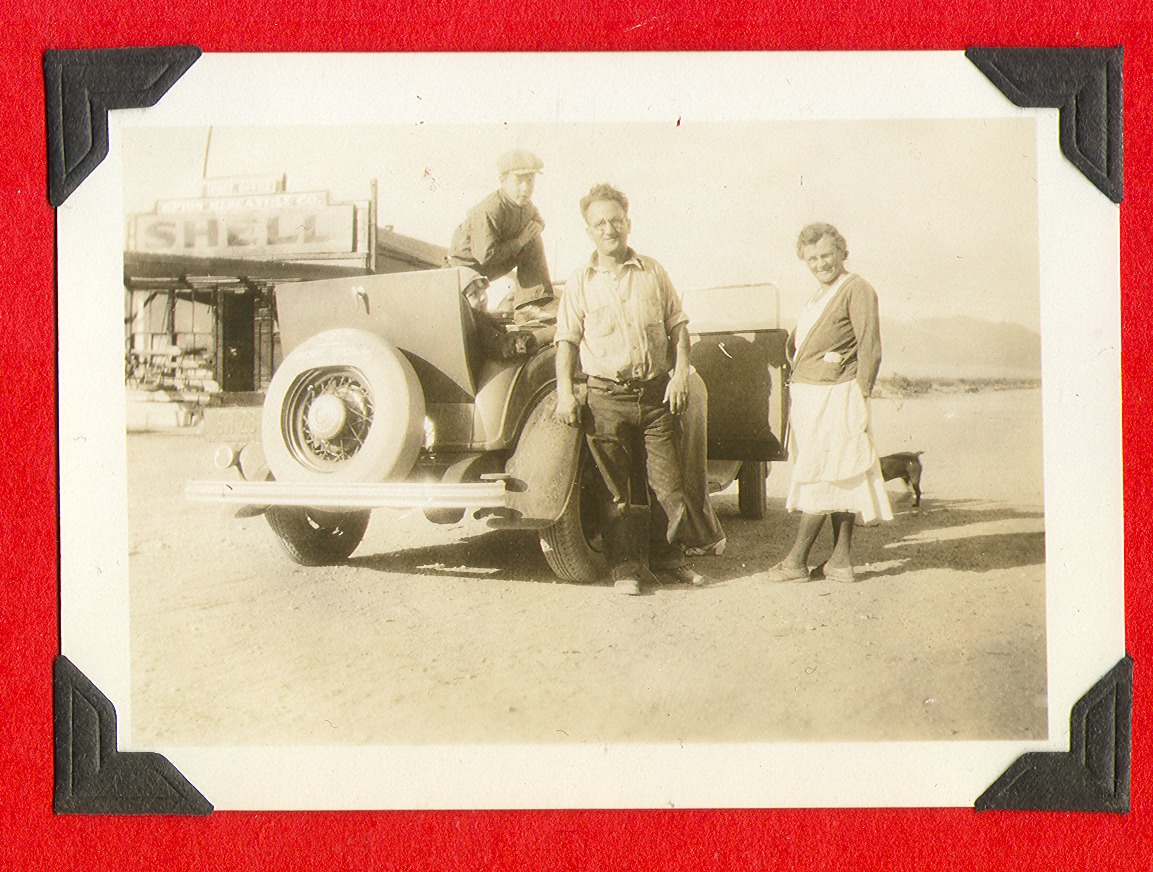 Three unidentified people standing next to a car: photographic print