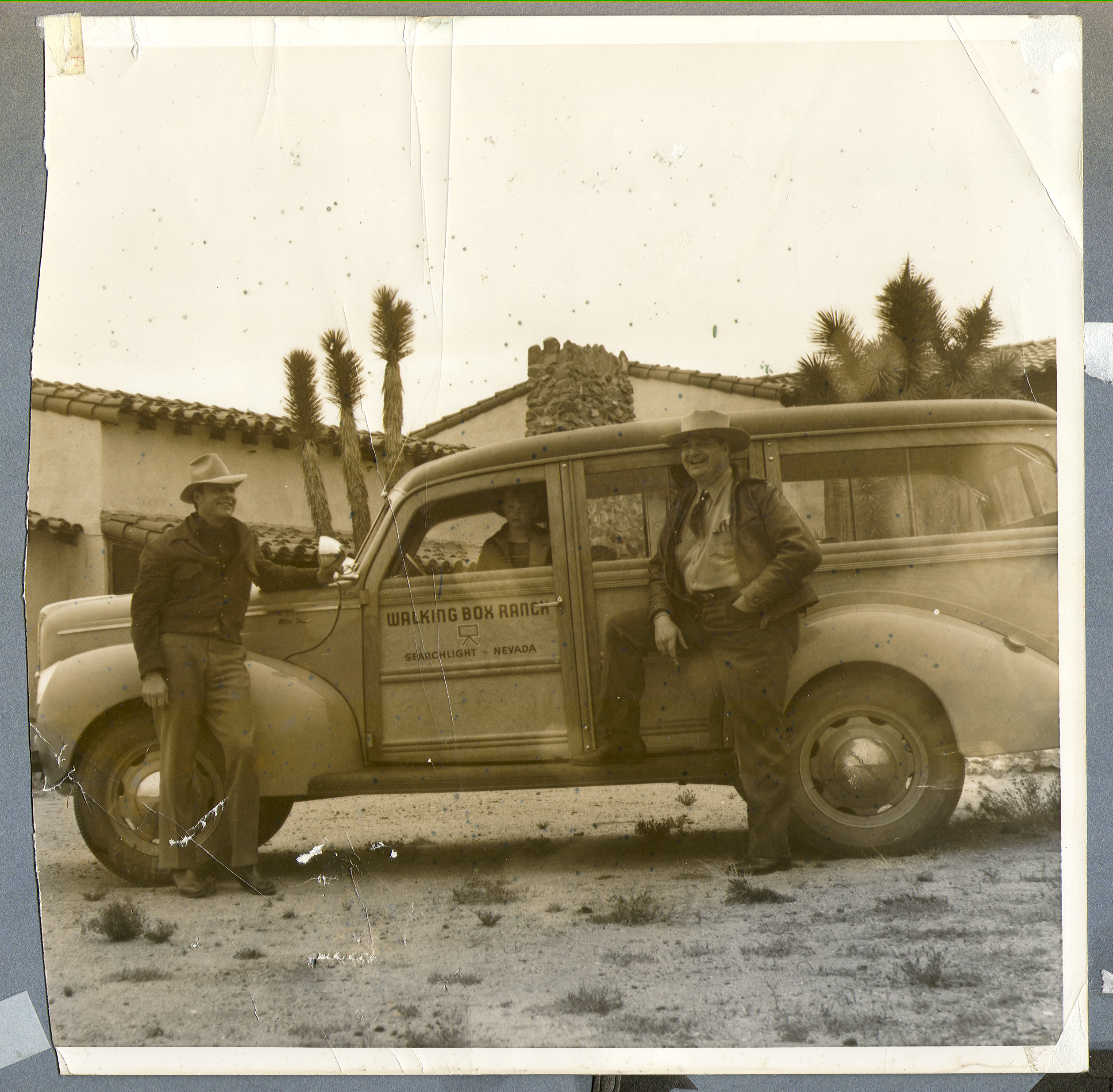 Vehicle with Walking Box Ranch, Searchlight, (Nev.) on the side. Rex Bell (left), Bill Froelich (right), and Rex Anthony Bell, Jr in the car: photographic print