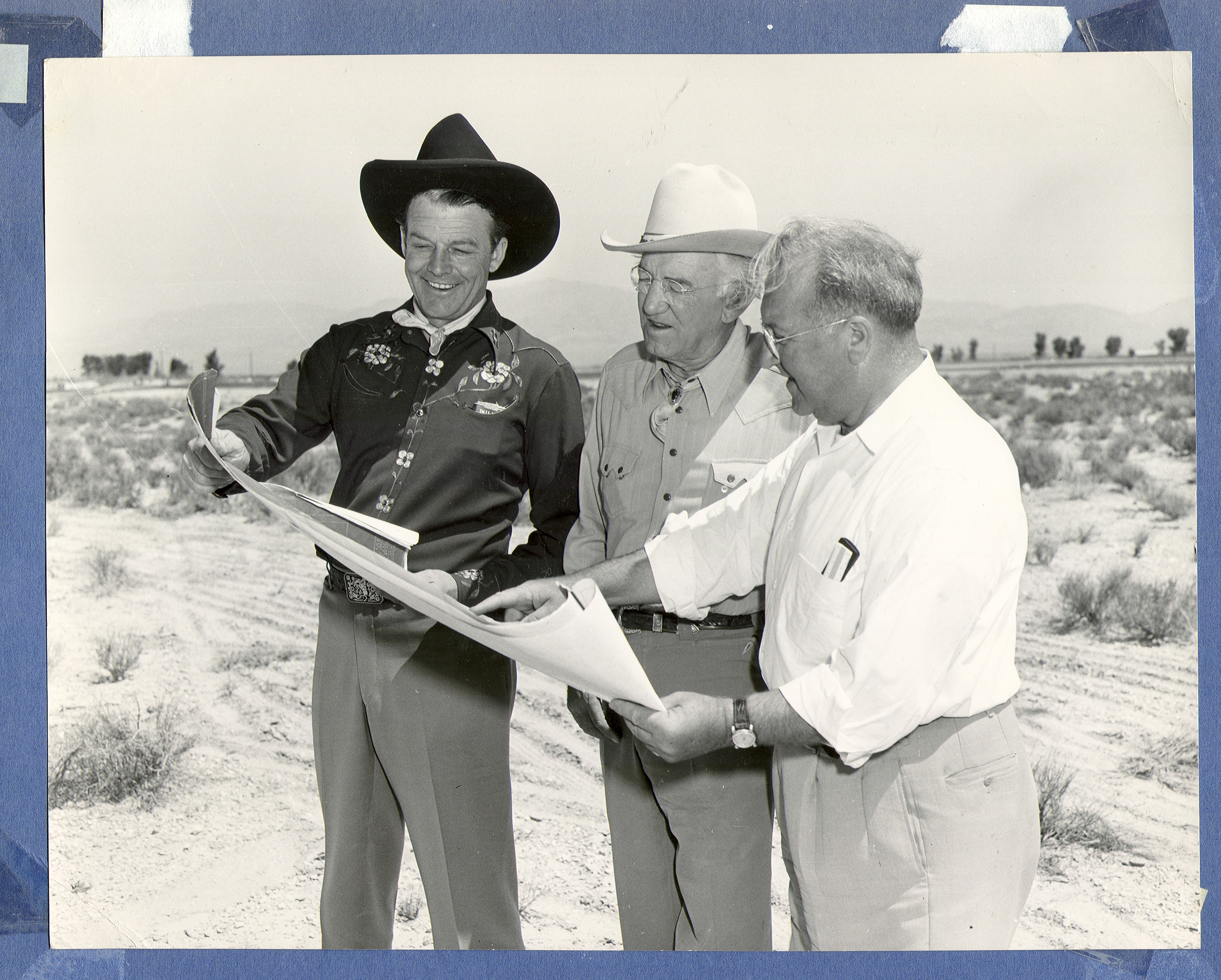 Rex Bell (left) with Mr. Wells looking at blueprints or plans of some sort: photographic print