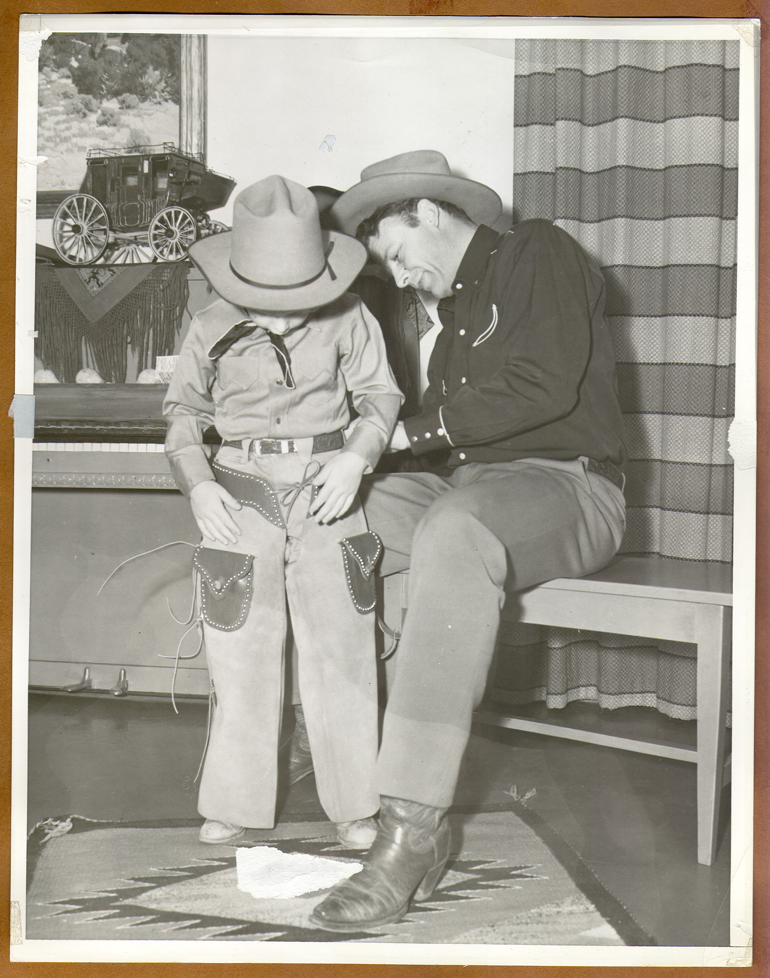 Rex Bell helping his son Rex Bell Jr. put on his cowboy gear: photographic print