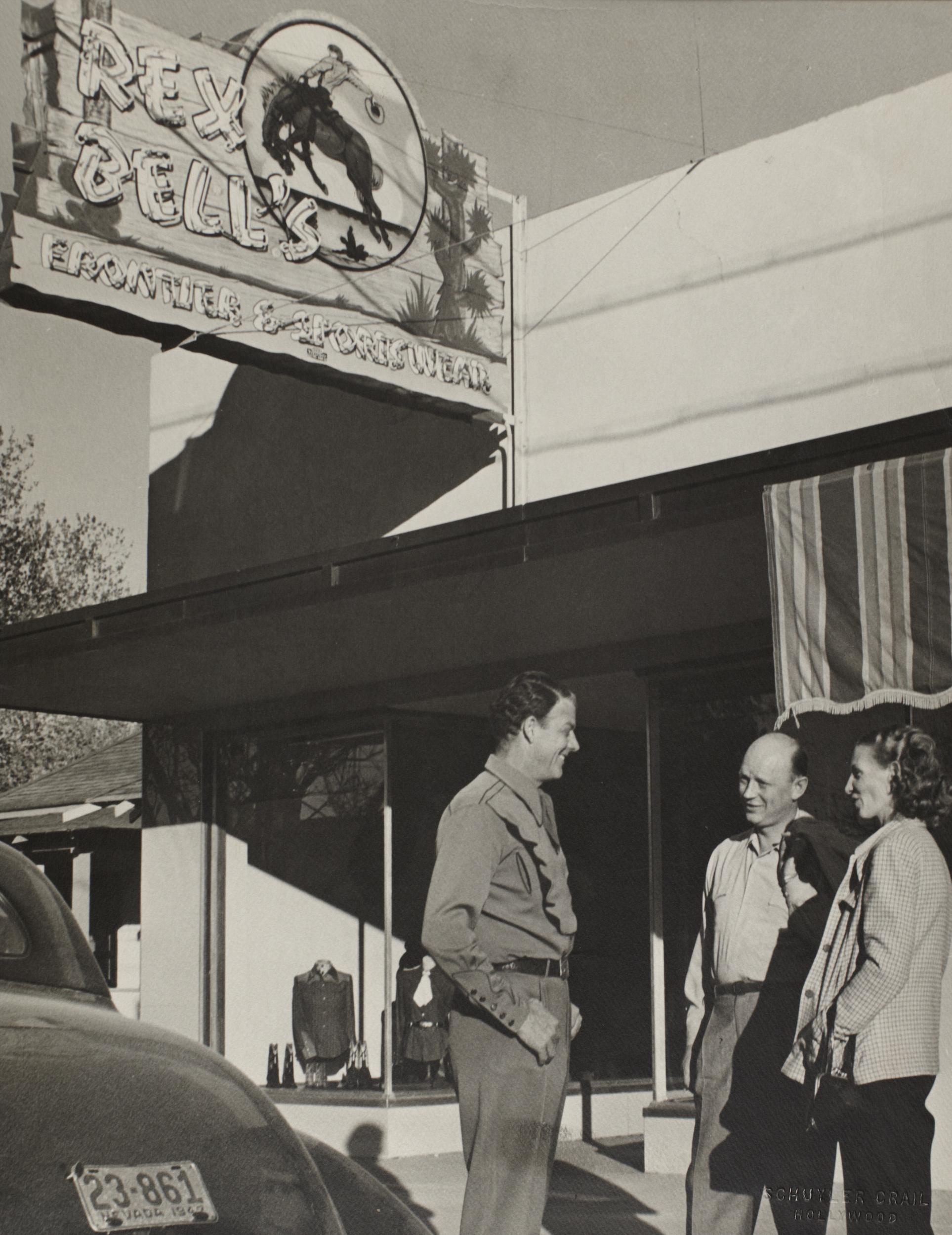 Rex Bell with two unidentified people outside of the "Rex Bell's Frontier & Sportswear" store in Las Vegas, Nevada: photographic print