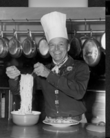 Rex Bell (George Francis Beldam) in a commercial kitchen and chef's hat making spagetti