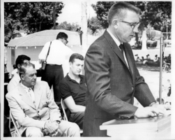Unidentified man giving a speech at an outdoor event.  Rex Bell (George Francis Beldam) is seated on the left