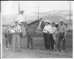 Group of people at a rodeo event. Rex Bell (George Francis Beldam) is on the left holding a trophy.  Other people and location are unidentified