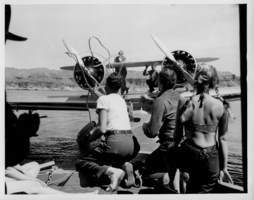 Group of people at Lake Mead helping to bring in an airplane. Rex Bell (George Francis Beldam) is kneeling on the right in front of the woman