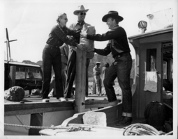 Rex Bell (George Francis Beldam) getting materials handed to him on a boat from two unidentified people.  Location is Lake Mead