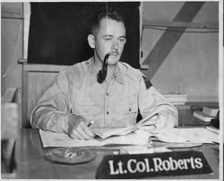 Photograph of Lt. Col. Roberts at a desk. Stamped on back: Headquarters, 9th Armored Division, Special Service Section