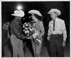 Rex Bell (George Francis Beldam) (left) with two unidentified people.  The woman has won some type of award at Helldorado. Stamped on back: Frank A. Maggio, Official Photographer for Twin Lakes Lodge & Stables, Las Vegas, NV