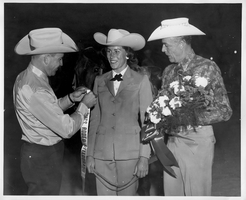 Rex Bell (George Francis Beldam) (left) with two unidentified people.  The woman has won some type of award at Helldorado. Stamped on back: Frank A. Maggio, Official Photographer for Twin Lakes Lodge & Stables, Las Vegas, Nevada