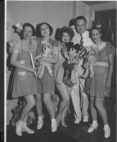 Clara Bow in costume (with Mickey Mouse toy) for a 1933 Hollywood party with four unidentified people in an unknown location