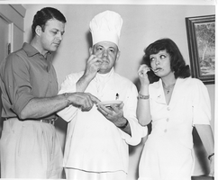 Rex Bell (George Francis Beldam) and Clara Bow with a chef (center) trying some food: photographic print 