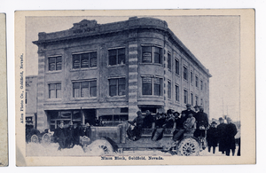 Postcard of people and automobiles in front of the Nixon Block Building, Goldfield (Nev.), 1900-1925