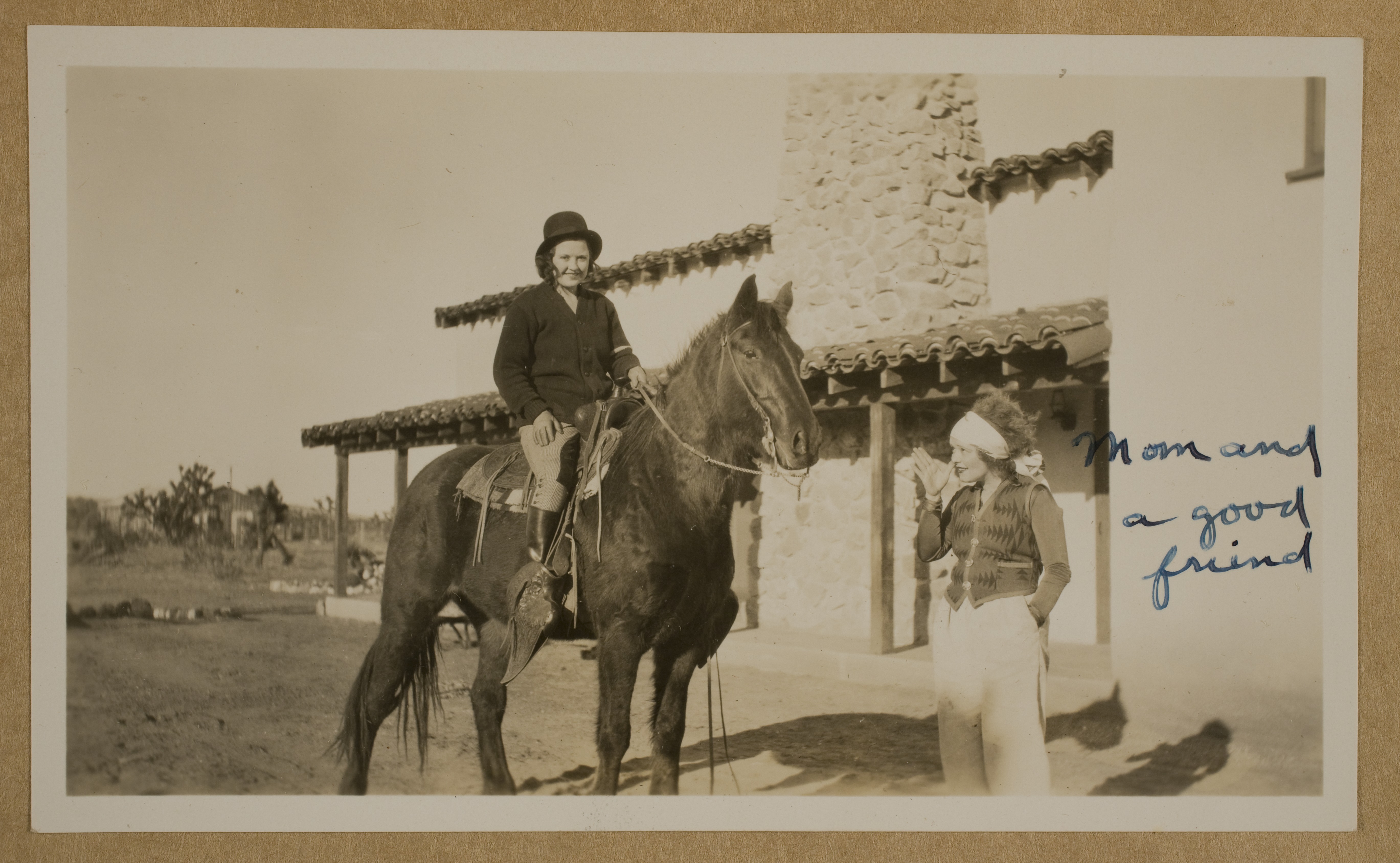 Marion Lewyn on horse in front of ranch house at Walking Box Ranch.  Clara Bow is standing next to her: photographic print