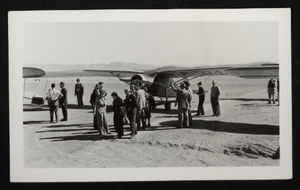 Photograph of people standing by a propeller airplane in the Boulder City, Nevada desert, circa 1930s