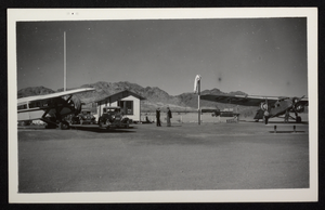 Photograph of men and automobiles on desert airfield with propeller airplanes, Boulder City, Nevada, circa 1930s