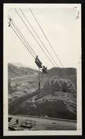 Photograph of man riding on cable hook to bottom of Black Canyon, Hoover Dam, circa 1930-1935
