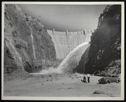 Photograph of two men looking at downstream face of Hoover Dam, circa 1934-1936