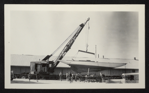 Photograph of sailboat being lifted by crane from railroad car, circa 1930s-1940s