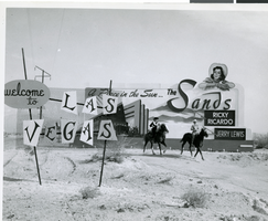 Photograph of early "Welcome to Las Vegas" sign, Sands Hotel and Casino billboard behind, circa 1952-1960s