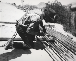 Photograph of a man cutting pipes to length or prepping them for welding, Hoover Dam, circa 1931