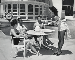 Photograph of a cocktail waitress serves drinks near the pool at the Showboat Hotel, Las Vegas, 1950s