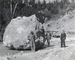 Photograph of men beside a boulder, circa late 1920s-1930s