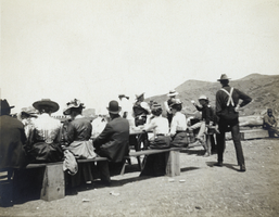 Photograph of people sitting at picnic tables, circa 1900-1920s