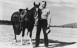 Photograph of George Malone posing beside Gimick the horse, Nevada, circa 1947-1959