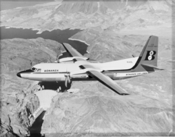 Film transparency of a twin-propeller airplane for Bonanza Air Lines, flying over Hoover Dam, Nevada, circa 1957