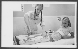 Photograph of Celeste Kohr removing a leg cast from a girl, Nellis Air Force Base, Nevada, August 18, 1976