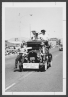 Photograph of Jack Petitti and others riding on a classic car in the North Las Vegas Parade, North Las Vegas, Nevada, circa 1960s